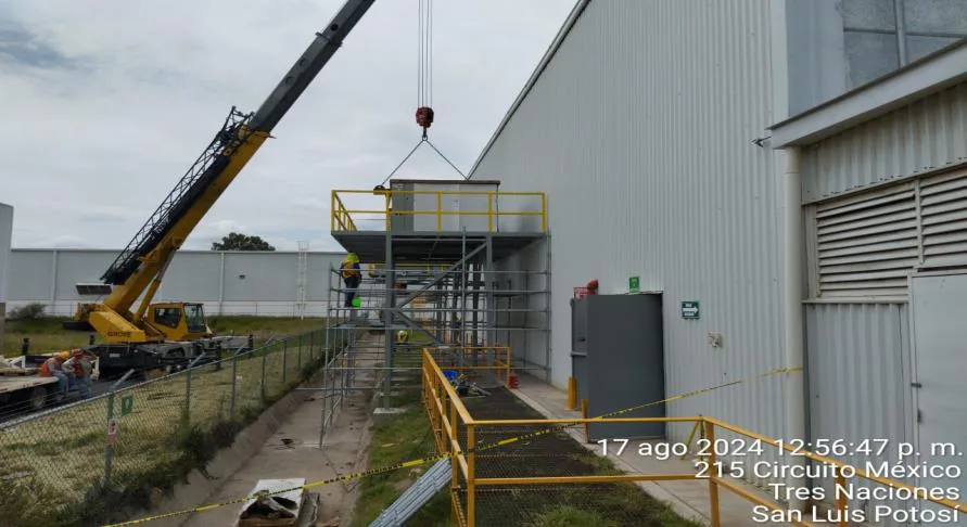 Montacargas amarillo maniobrando una unidad HVAC dentro de una planta en operación