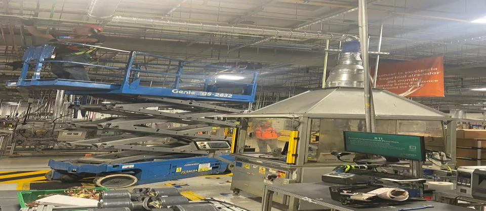 Plataformas de tijera junto a campana de acero inoxidable en una línea de producción
